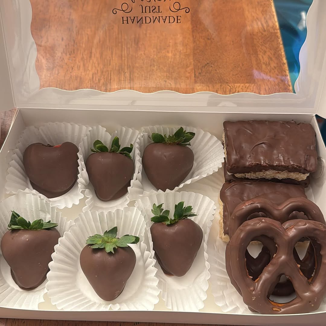 Assorted chocolate-covered treats box with six milk chocolate strawberries, two Rice Krispie bars, and two pretzels arranged in a white bakery box with paper liners.