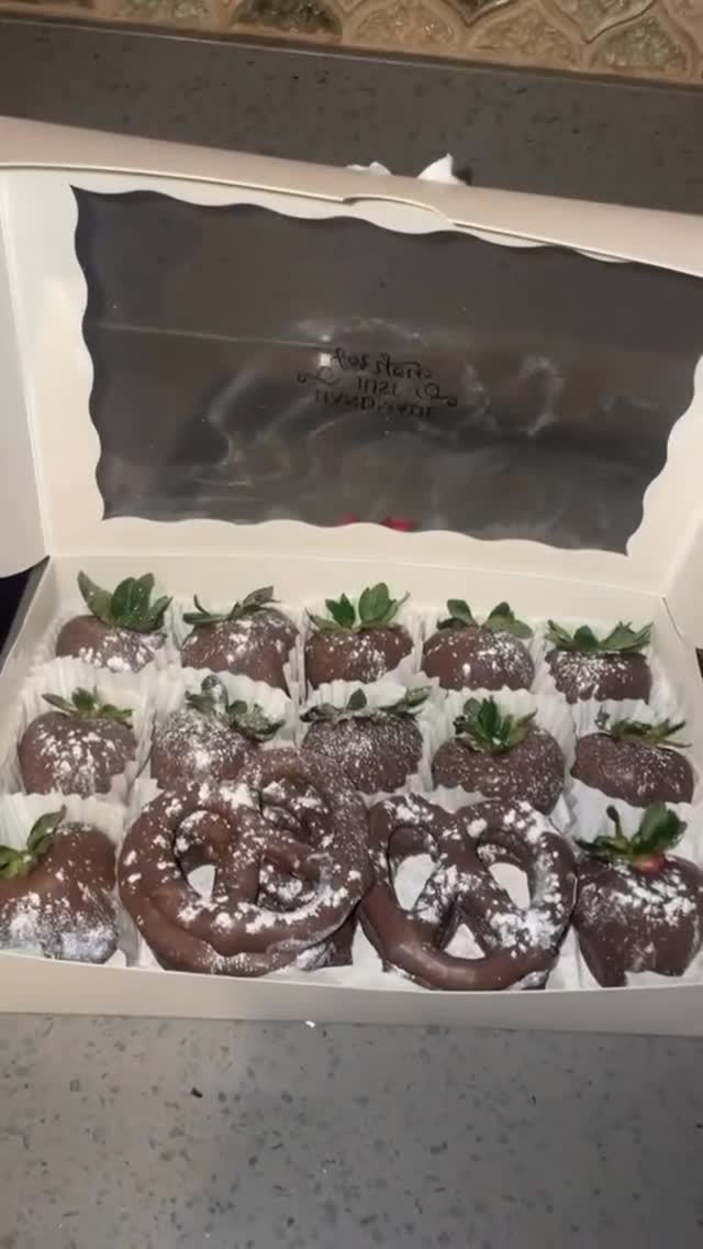 Assorted box of nine dark chocolate strawberries and two large chocolate-covered pretzels, all dusted with powdered sugar shimmer.