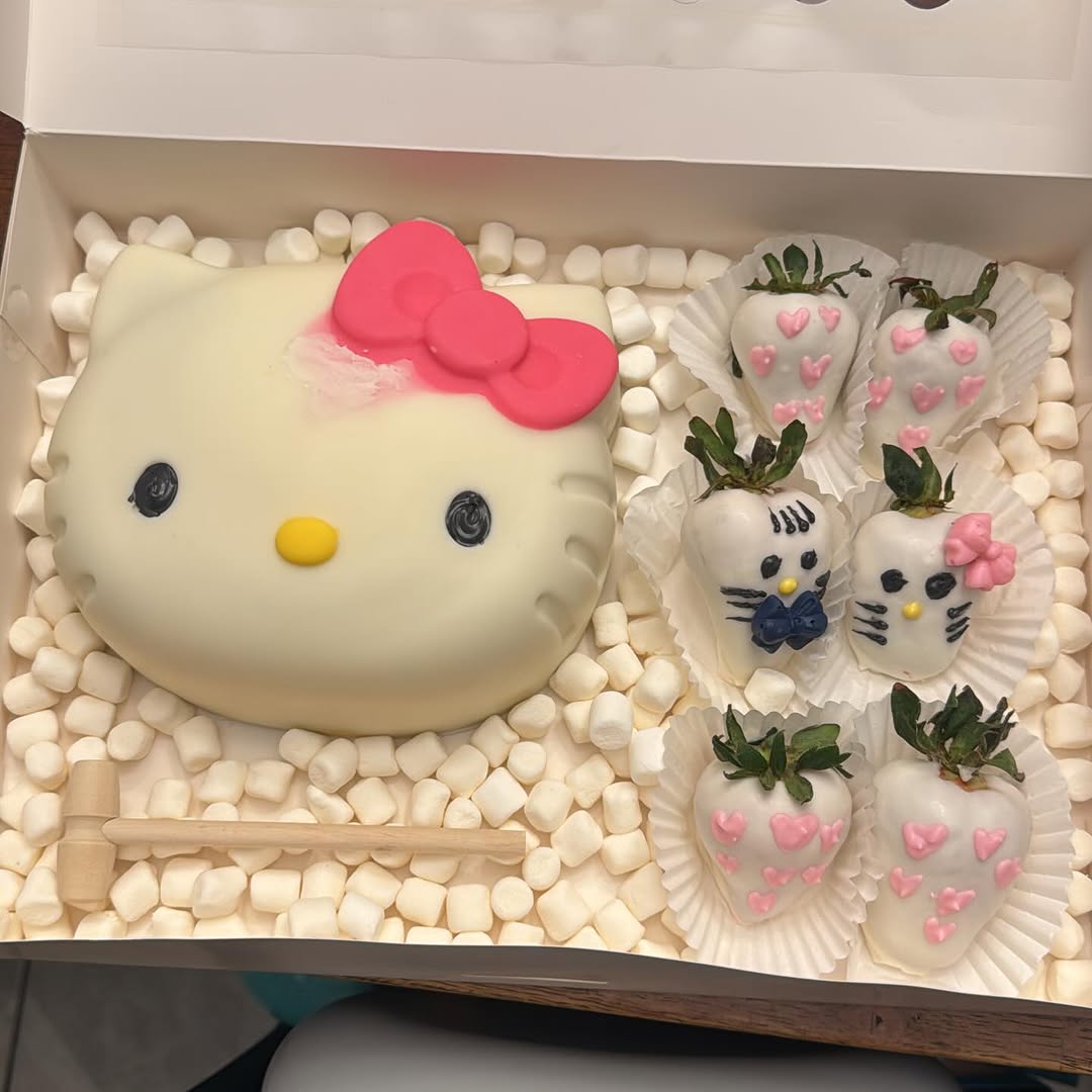 Hello Kitty breakable chocolate shell with pink bow, six themed white chocolate strawberries with hearts and bows, and a wooden mallet for smashing.