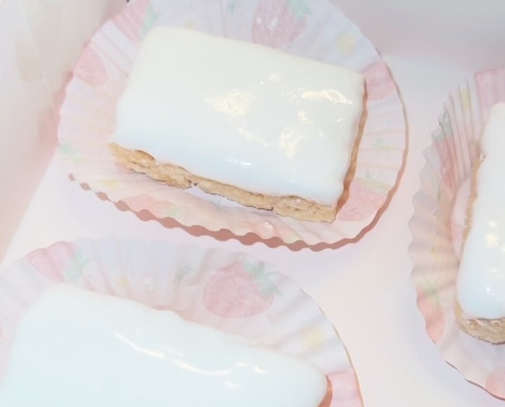 Close-up of a single white chocolate Rice Krispie treat bar showing the glossy coating and crispy rice texture visible on the sides.
