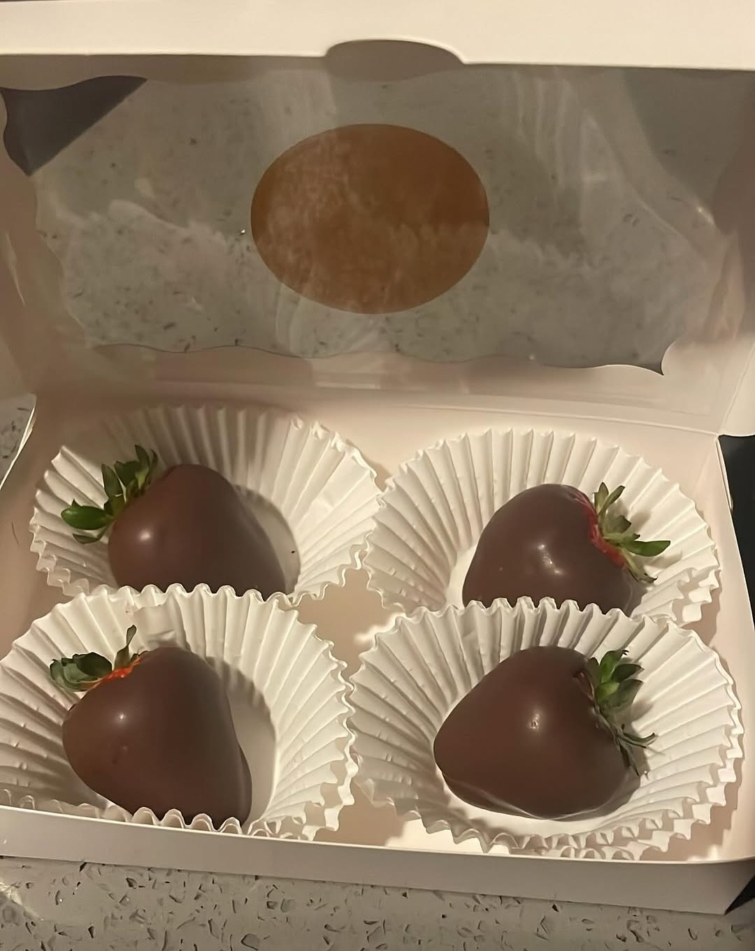 Four classic milk chocolate-covered strawberries with a clean, minimalist presentation in a small white bakery box.