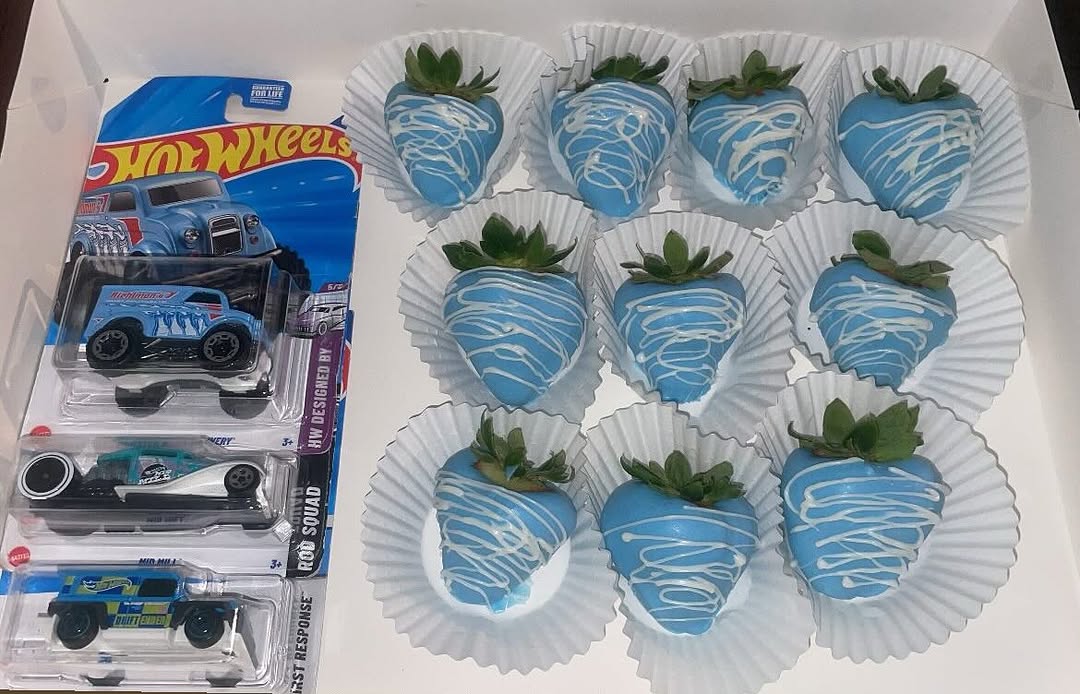 Baby blue chocolate-covered strawberries with white drizzle paired with Hot Wheels toy cars, a themed birthday gift box for boys.