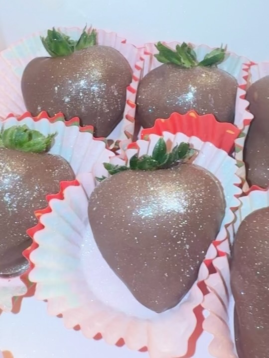 Close-up of dark chocolate-covered strawberries with fine gold and silver iridescent luster dust, showcasing the elegant shimmer finish.